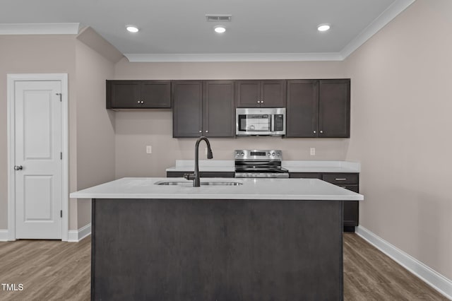 kitchen featuring appliances with stainless steel finishes, an island with sink, dark wood-type flooring, and sink