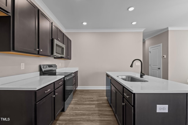 kitchen featuring dark wood-type flooring, a center island with sink, crown molding, sink, and appliances with stainless steel finishes