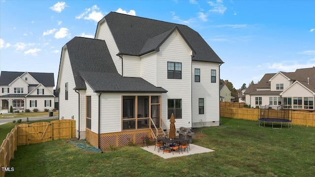 rear view of house with a yard, a sunroom, a trampoline, and a patio