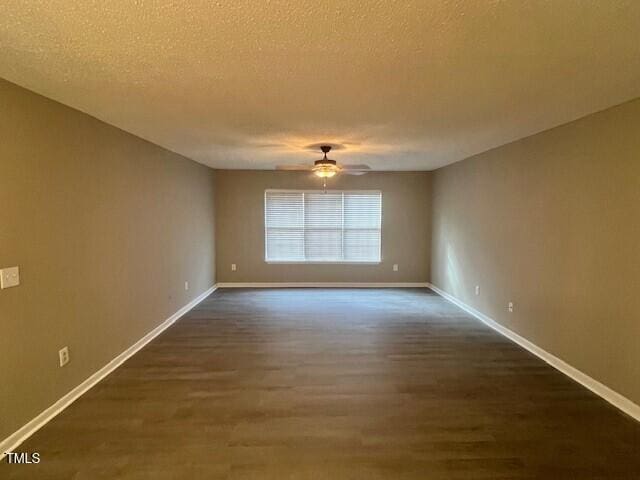 spare room with a textured ceiling, ceiling fan, and dark wood-type flooring