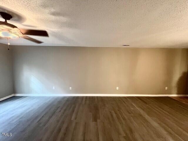 empty room with ceiling fan, a textured ceiling, and dark wood-type flooring