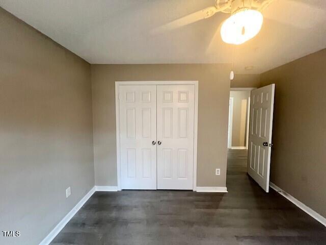 unfurnished bedroom featuring a closet, dark wood-type flooring, and ceiling fan