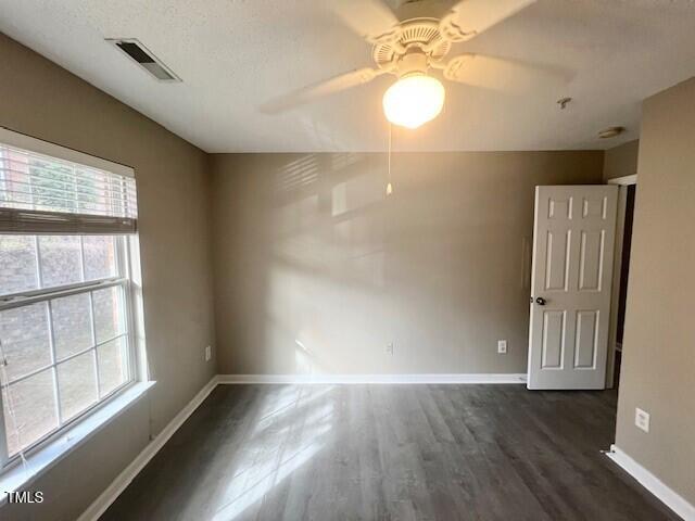 unfurnished room with a textured ceiling, ceiling fan, and dark wood-type flooring