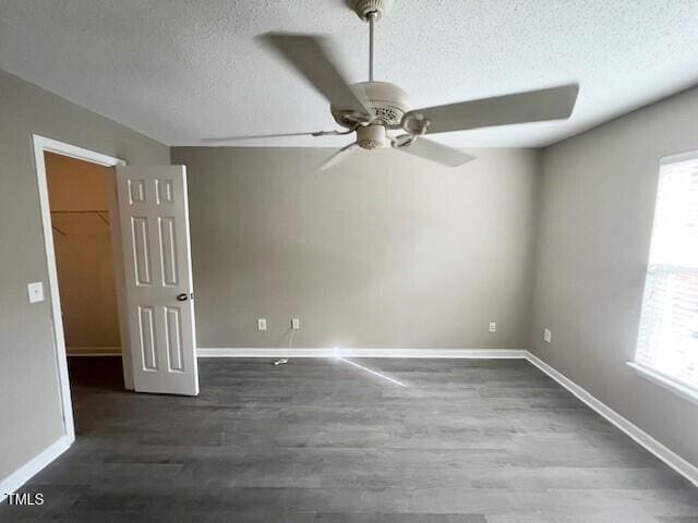 unfurnished room with ceiling fan, dark wood-type flooring, and a textured ceiling