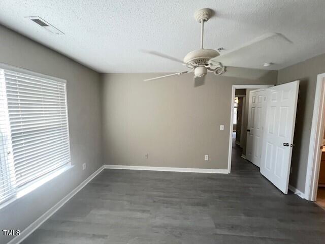 empty room with a textured ceiling, ceiling fan, and dark wood-type flooring