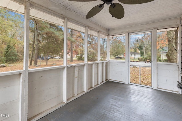 unfurnished sunroom featuring wood ceiling, ceiling fan, and a healthy amount of sunlight