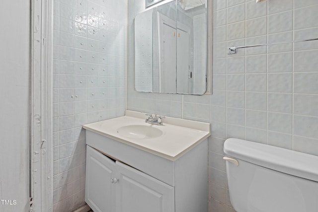 bathroom featuring vanity, toilet, and tile walls