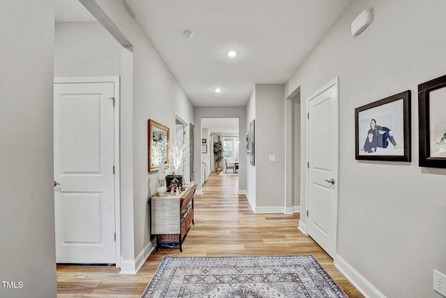 corridor featuring light wood-type flooring, baseboards, and recessed lighting