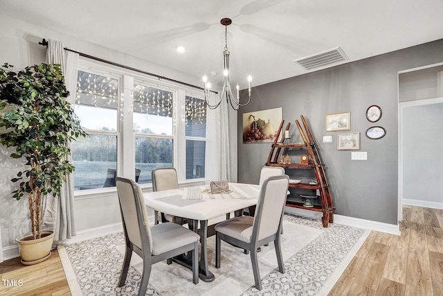 dining area featuring light hardwood / wood-style floors and a notable chandelier