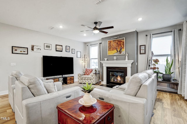 living room featuring a premium fireplace, recessed lighting, visible vents, and light wood-style floors