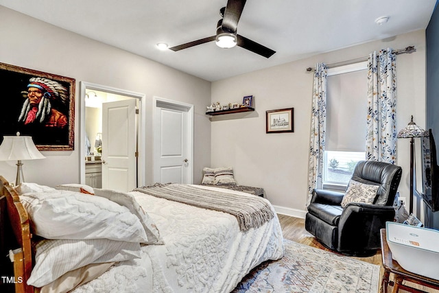 bedroom featuring ceiling fan, ensuite bath, baseboards, and wood finished floors