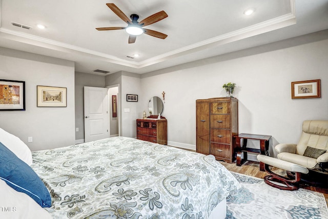 bedroom featuring a tray ceiling, ceiling fan, crown molding, and wood-type flooring