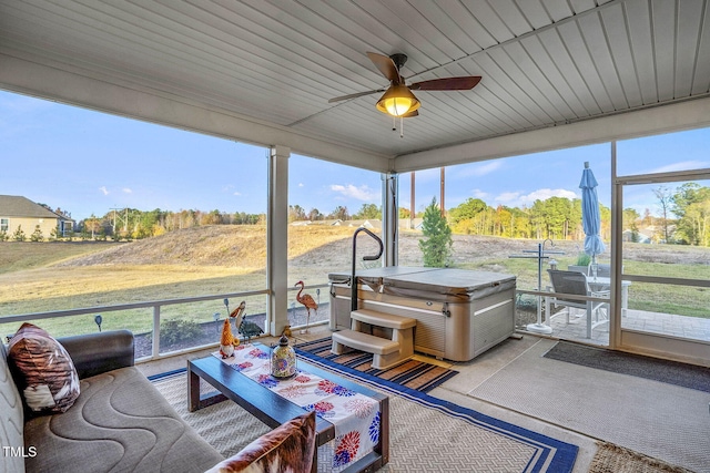 sunroom / solarium with a wealth of natural light, ceiling fan, wooden ceiling, and a rural view