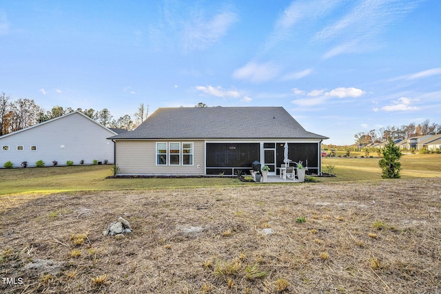 rear view of property featuring a sunroom, a patio, and a lawn