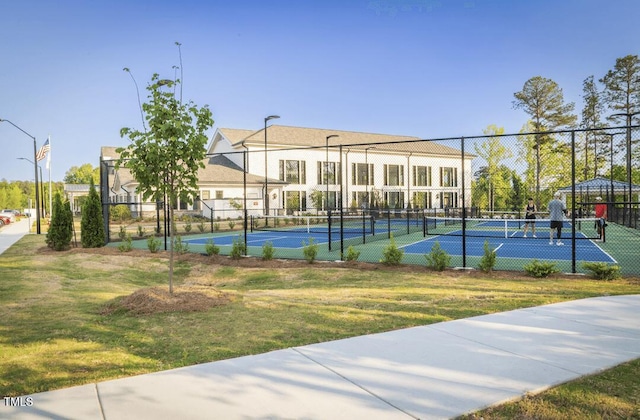 view of sport court with a lawn and fence