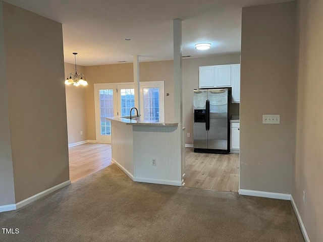 kitchen featuring stainless steel fridge, an inviting chandelier, light hardwood / wood-style flooring, white cabinetry, and hanging light fixtures