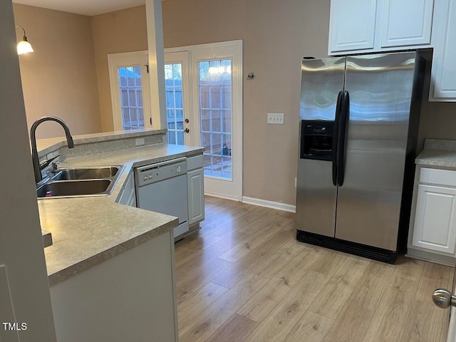 kitchen with dishwasher, stainless steel fridge, white cabinets, and sink