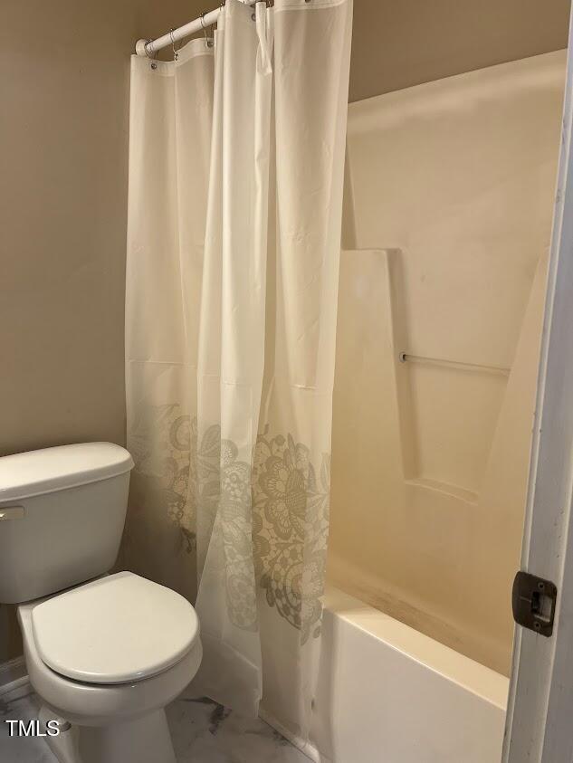 bathroom featuring toilet and shower / bathtub combination with curtain