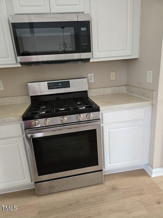 kitchen with white cabinetry, appliances with stainless steel finishes, and light hardwood / wood-style flooring