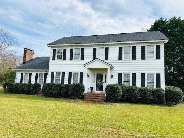 colonial inspired home featuring a front lawn