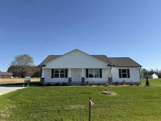 view of front of house with a front yard, roof with shingles, and covered porch