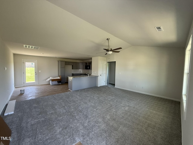 unfurnished living room with dark carpet, visible vents, a ceiling fan, and lofted ceiling