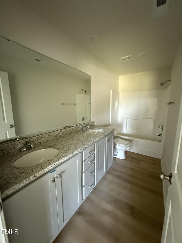 bathroom featuring double vanity, visible vents, a sink, and toilet