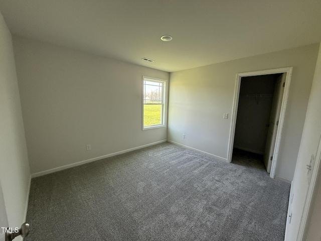 unfurnished bedroom featuring baseboards, a spacious closet, visible vents, and carpet floors