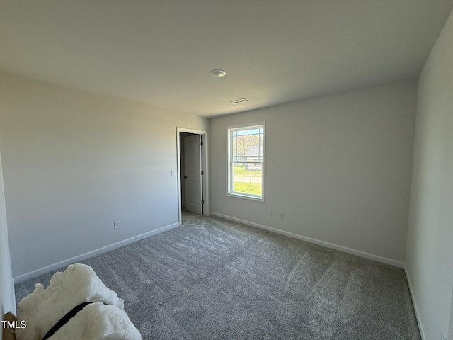 empty room featuring carpet floors, baseboards, and visible vents