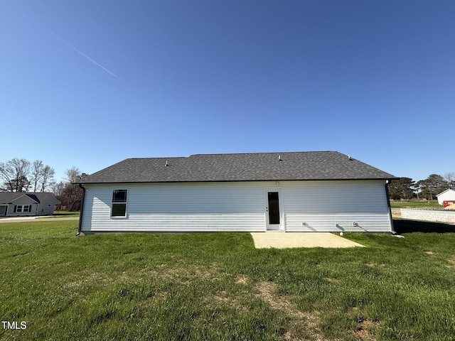 back of property with roof with shingles and a lawn