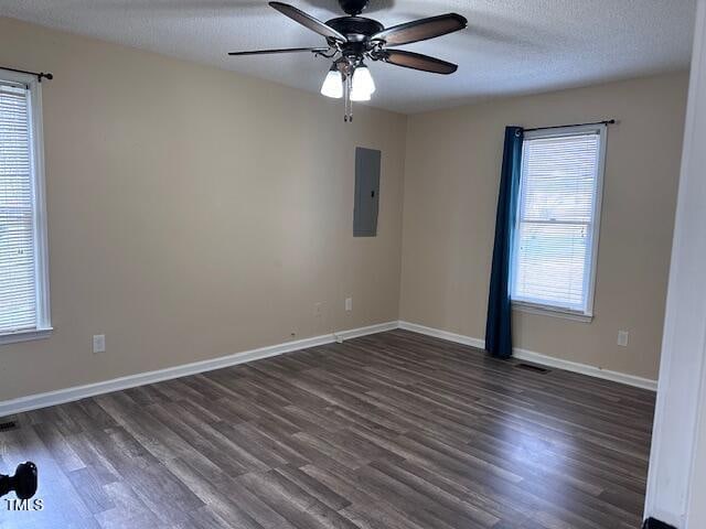 spare room with ceiling fan, dark hardwood / wood-style flooring, a textured ceiling, and electric panel