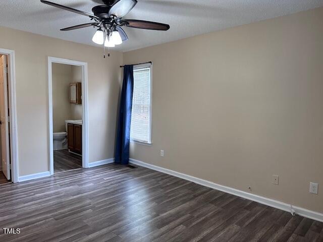 unfurnished bedroom with connected bathroom, ceiling fan, dark wood-type flooring, and a textured ceiling