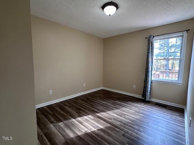 empty room featuring dark hardwood / wood-style flooring and a textured ceiling