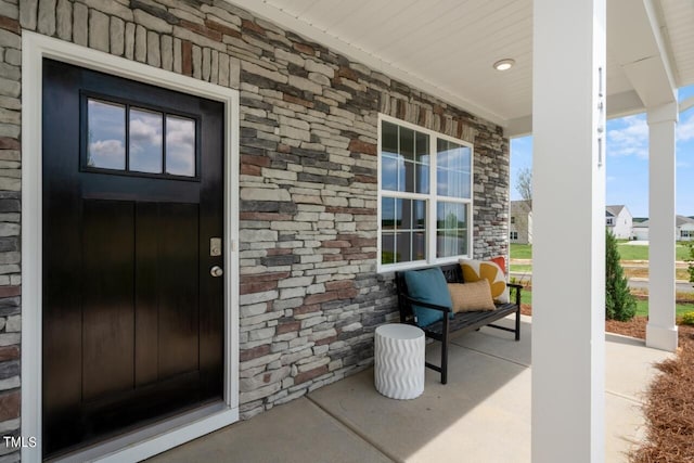 view of exterior entry featuring a porch and stone siding