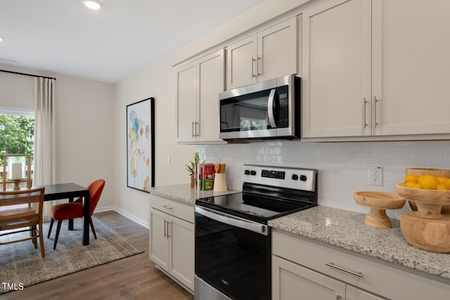 kitchen with appliances with stainless steel finishes, backsplash, dark wood-type flooring, baseboards, and light stone counters