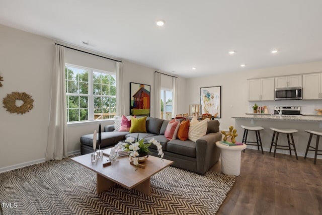 living room featuring recessed lighting, dark wood-type flooring, and baseboards