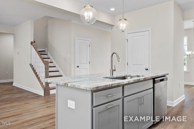 kitchen with sink, gray cabinetry, a center island with sink, stainless steel dishwasher, and pendant lighting