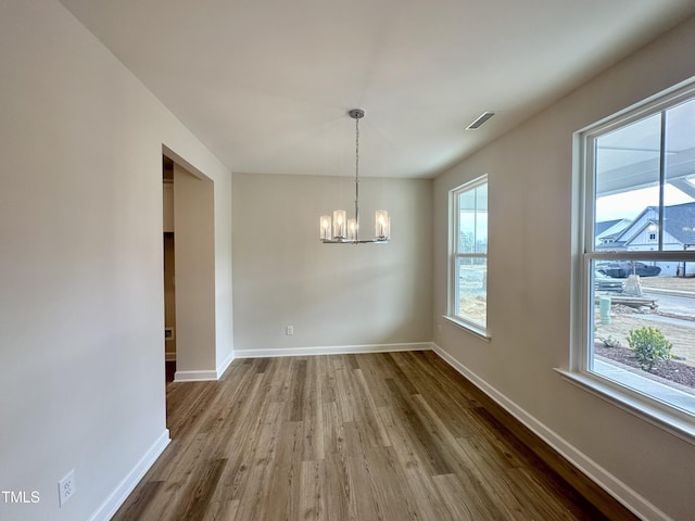 unfurnished dining area featuring hardwood / wood-style floors and an inviting chandelier