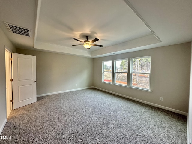 carpeted empty room with ceiling fan and a tray ceiling