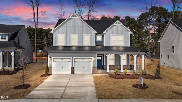 modern farmhouse featuring concrete driveway, an attached garage, a porch, board and batten siding, and brick siding