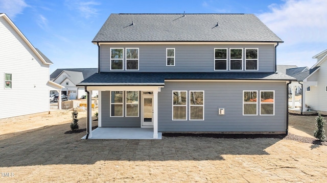 rear view of house featuring a shingled roof and a patio