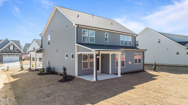 rear view of house with central AC unit, roof with shingles, and a patio area