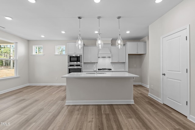 kitchen with light wood-style flooring, built in microwave, light countertops, stainless steel oven, and a sink