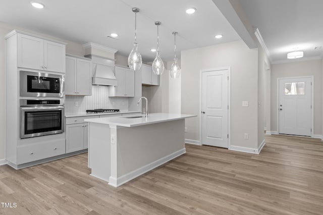 kitchen with gas stovetop, tasteful backsplash, light wood-style flooring, black microwave, and oven