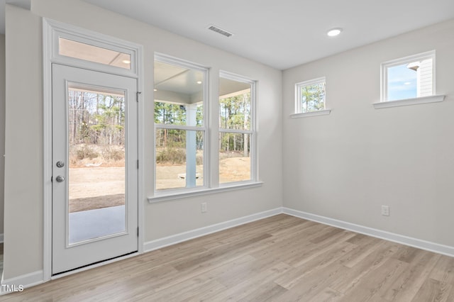 doorway featuring light wood finished floors, visible vents, and baseboards