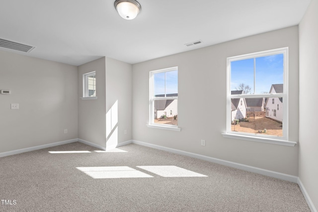 empty room featuring carpet, visible vents, and baseboards