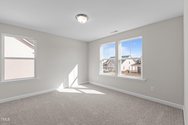 unfurnished room with carpet floors, visible vents, and baseboards