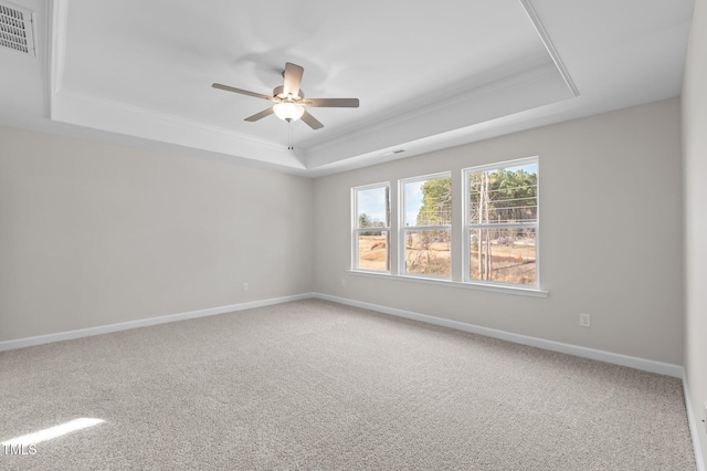 spare room featuring carpet, visible vents, a raised ceiling, and baseboards