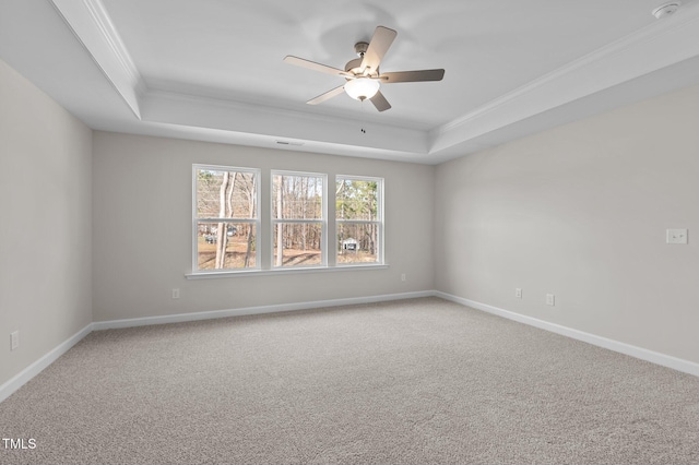 carpeted spare room with a ceiling fan, baseboards, a raised ceiling, and crown molding