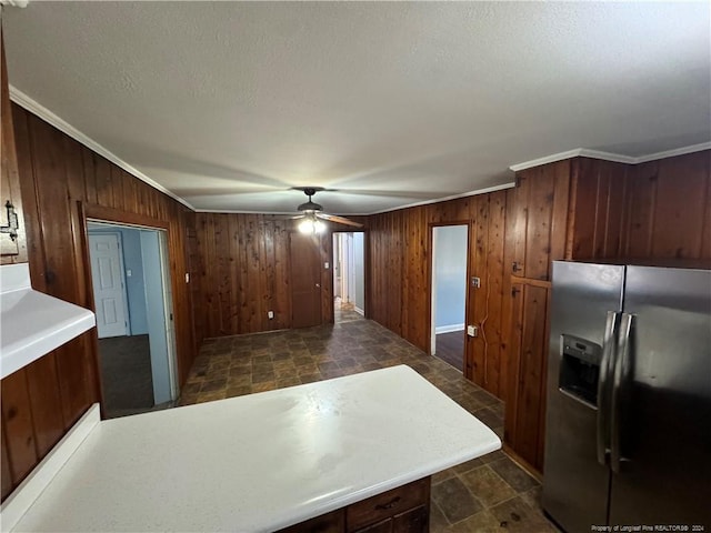 kitchen featuring stainless steel fridge, crown molding, ceiling fan, and wood walls